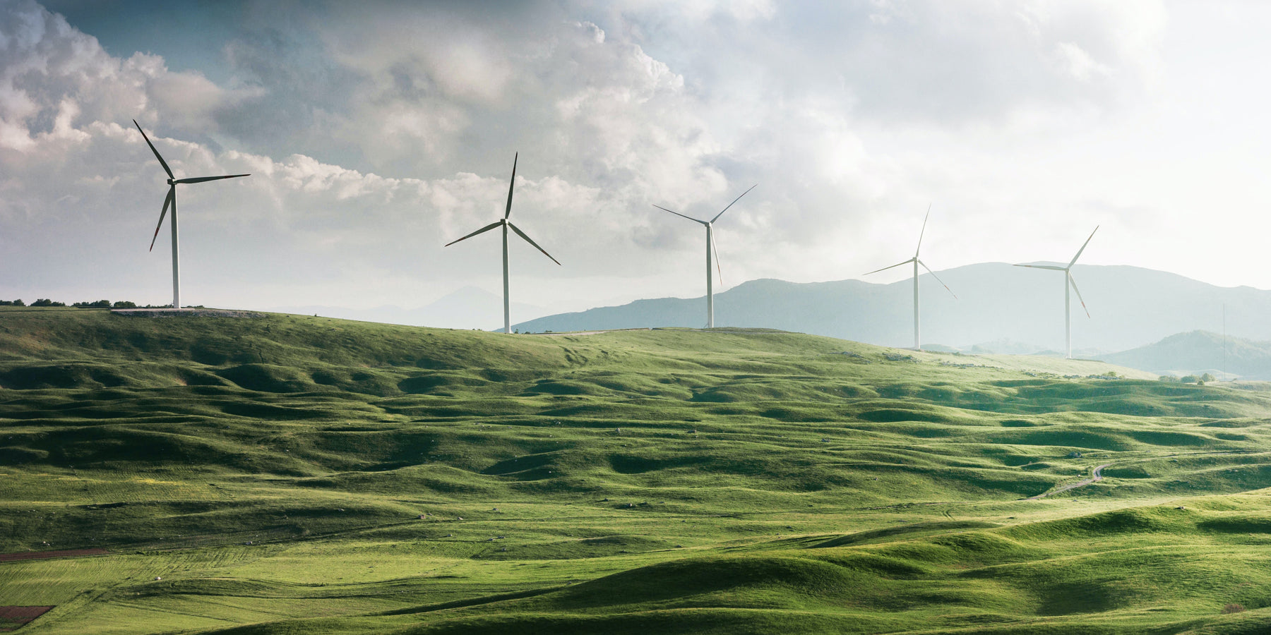 A scenic green hill adorned with wind turbines, harnessing renewable energy and contributing to a sustainable future.