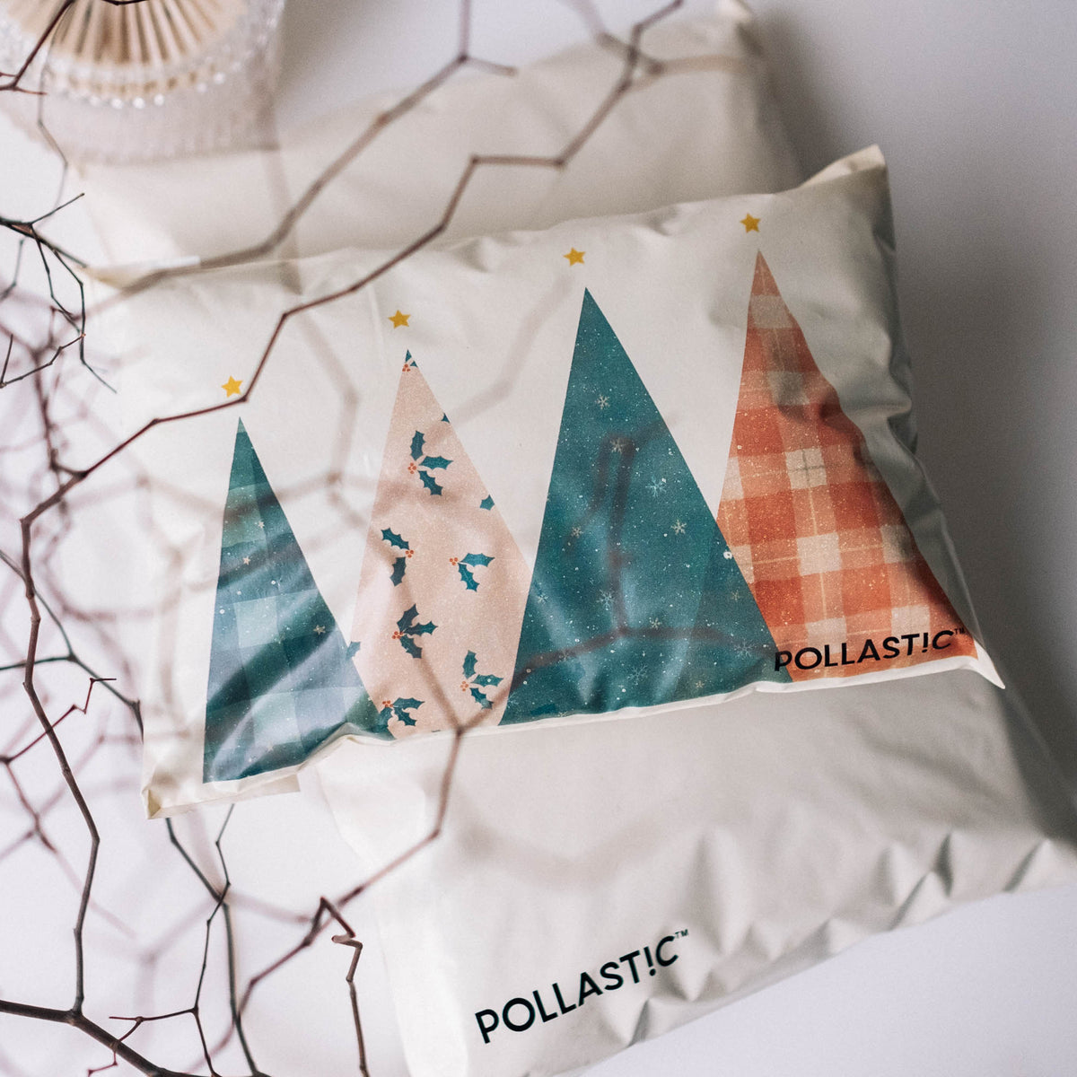 Close up shot of a cream Better Packaging POLLAST!C Christmas mailer with geometric Christmas trees